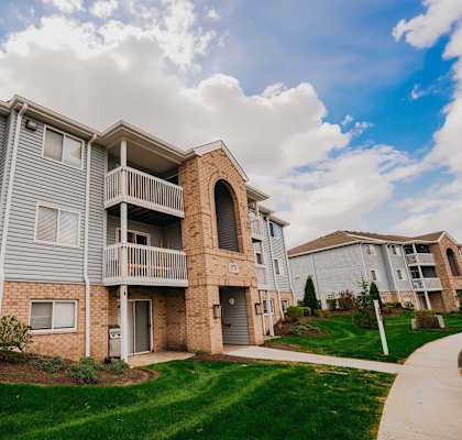 A residential building with a balcony and a small garden in front.