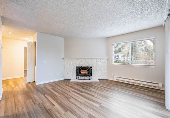 A room with a fireplace and wood flooring.