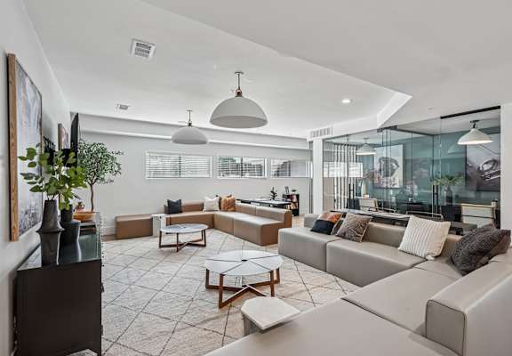 A modern living room with a grey sofa set and a glass table.