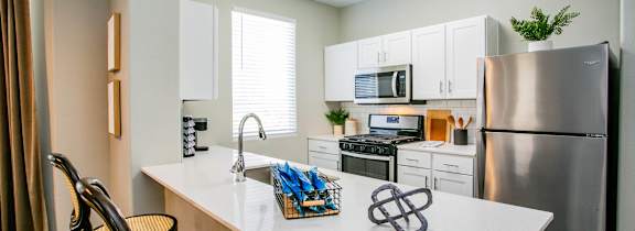 A kitchen with a white countertop and a stainless steel refrigerator.