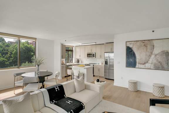 A modern living room with a white couch and a large painting on the wall.
