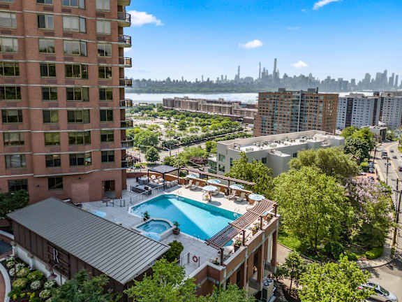 A view of a pool area from a high angle with a city skyline in the background.