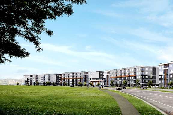 A row of modern apartment buildings with a green lawn in front.