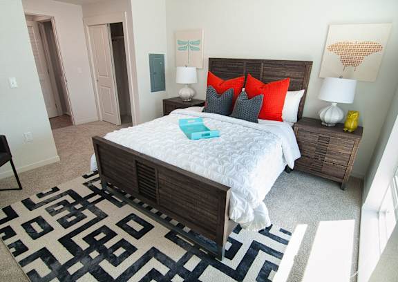 A bedroom with a large bed and a patterned rug.
