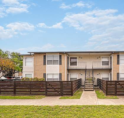 a brick apartment building with a wooden fence in front of it