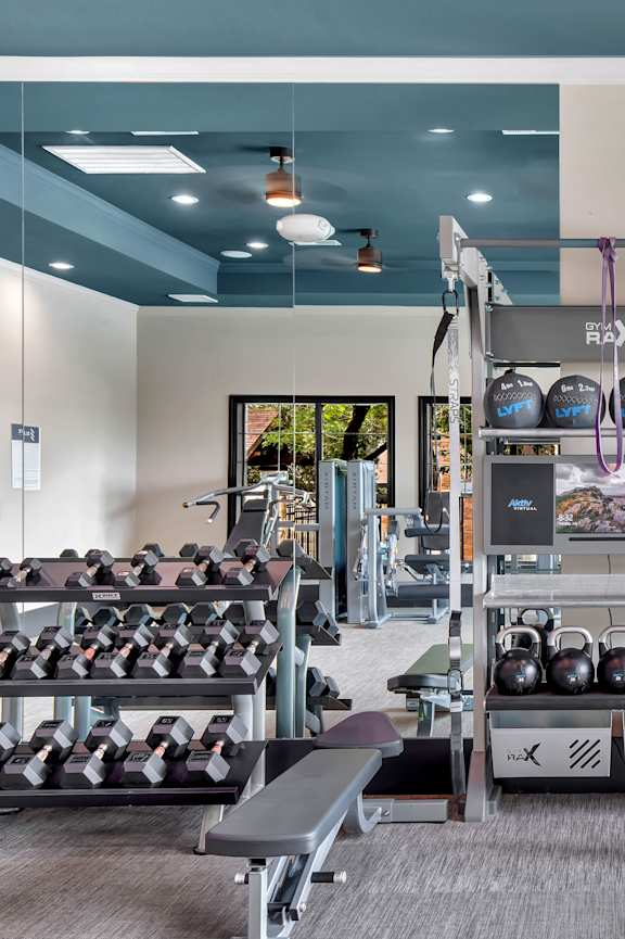 A gym with a variety of equipment including weights, a rowing machine, and a treadmill.