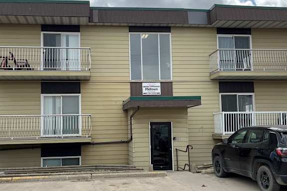 A black car is parked in front of a building with a sign that says "Midtown.".