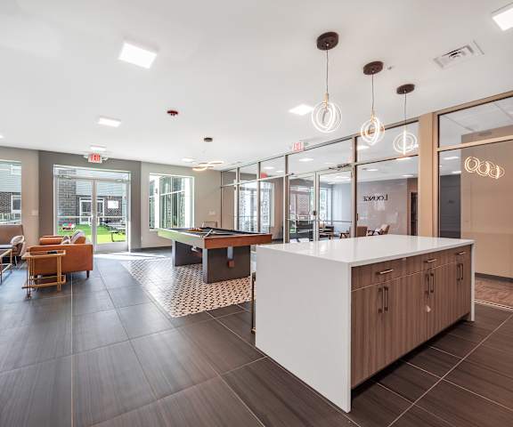 A reception area with a white counter and brown chairs.