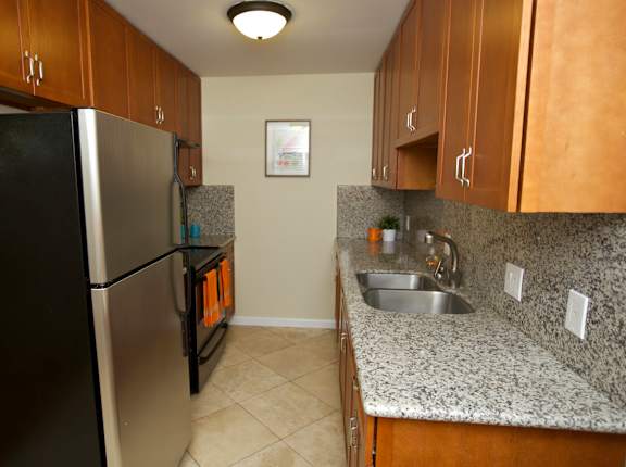 a kitchen with granite counter tops and a stainless steel refrigerator