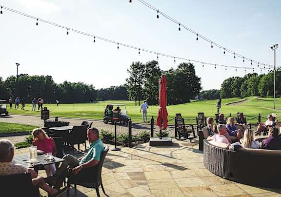 People relaxing on the outdoor patio near the golf course at the Grandover Resort and Spa
