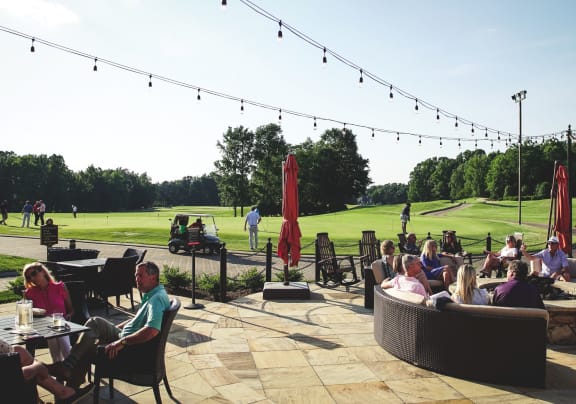 People relaxing on the outdoor patio near the golf course at the Grandover Resort and Spa