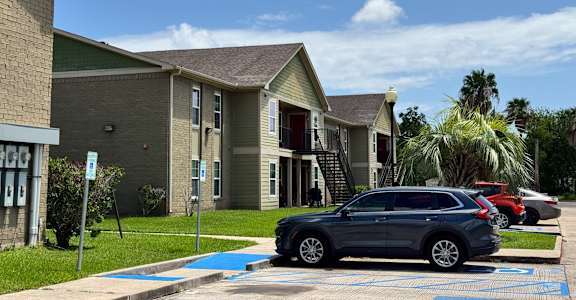 A grey car is parked in a blue marked parking spot.