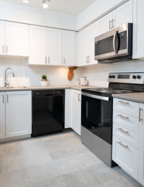 a kitchen with white cabinets and black appliances