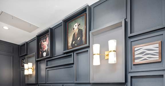 a long seating area with leather chairs and a blue wall with paintings