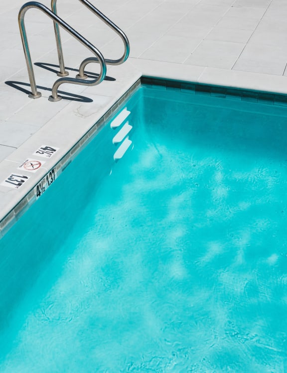 Up close of blue pool with water ripples and grey ledge. 