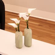 Two vases with white flowers sit on a table.