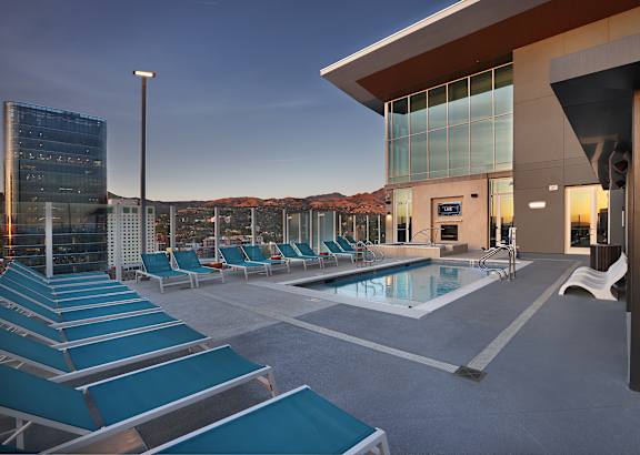 A modern building with a pool and lounge chairs.
