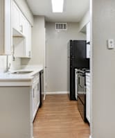 A kitchen with white cabinets and black appliances. at Helios, Dallas, TX, 75240