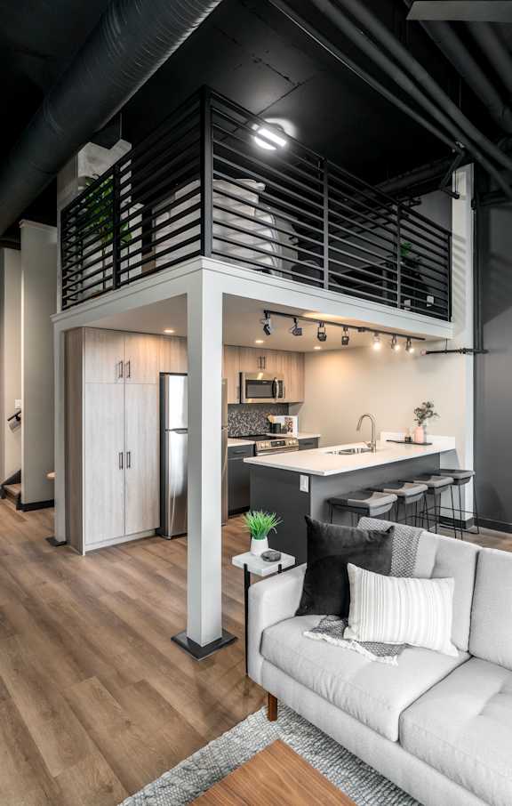 A modern kitchen with a white couch and wooden floors.at Raymond Block, Edmonton Alberta T6E 3R7