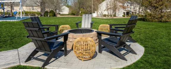 a fire pit with chairs around it in the middle of a lawn