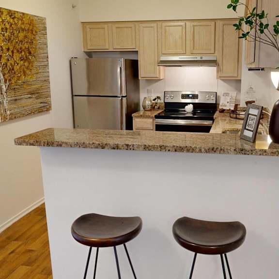 A kitchen with a granite countertop and two bar stools.