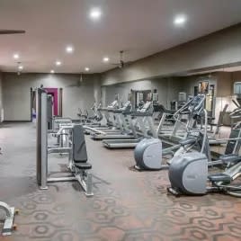 a gym with cardio equipment and weights on the floor