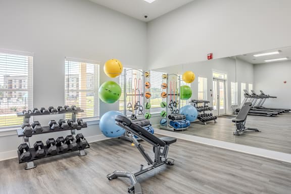 a gym with exercise equipment and weights on the floor and a large window