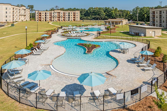 an aerial view of a large swimming pool with umbrellas and chairs around it