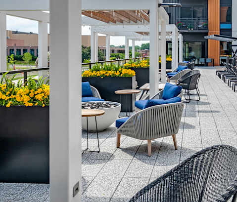 A patio with chairs and tables is covered with a white roof.