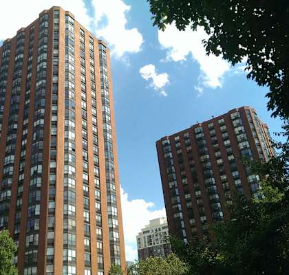 A tall building with many windows is surrounded by trees.