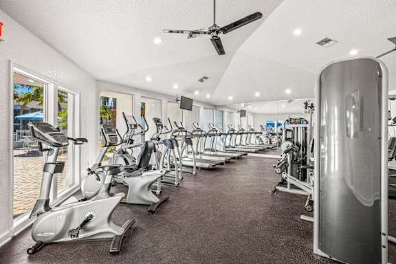 A gym with a row of treadmills and elliptical machines.