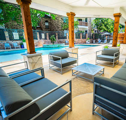 a patio with couches and chairs and a pool in the background