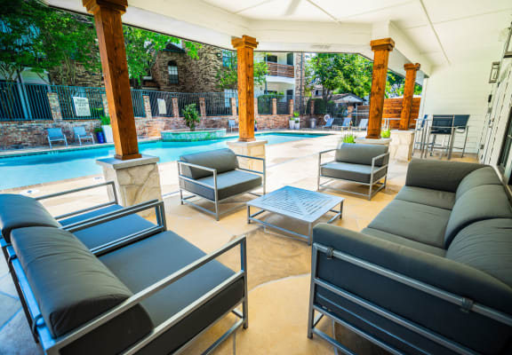 a patio with couches and chairs and a pool in the background