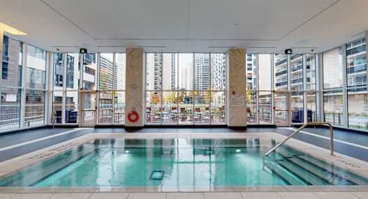 A large indoor swimming pool with a view of the city outside the windows.