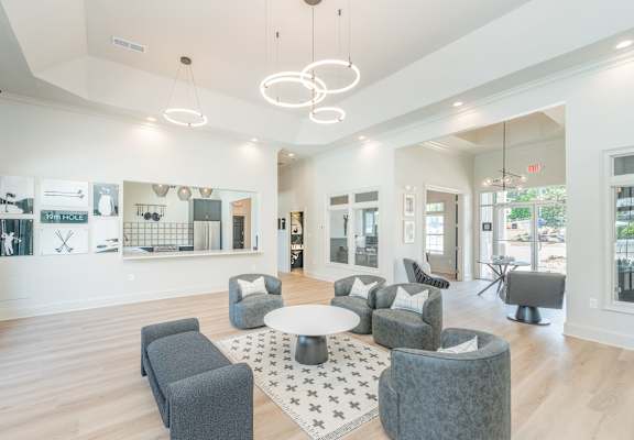 A spacious waiting area with grey couches and a white rug.