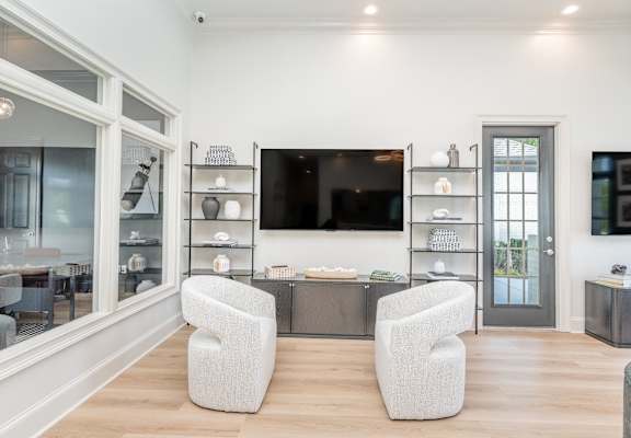 A modern living room with a television, two chairs, and a coffee table.