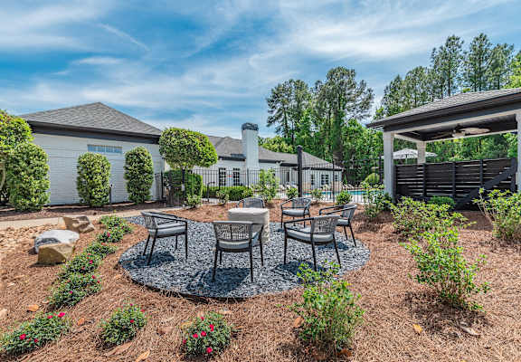 A backyard with a patio table set and a house in the background.