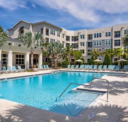 A large swimming pool in front of a building with palm trees.