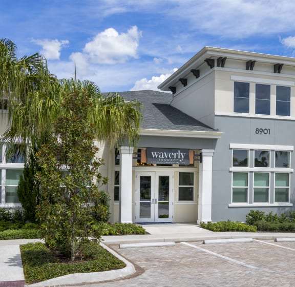 a gray building with palm trees in front of it  at Waverly Terrace Luxury Apartments in Florida