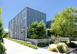 a large gray building with trees and bushes in front of it