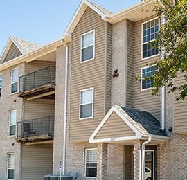 an apartment building with tan siding and a black roof