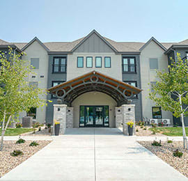 the front entrance of an apartment building with a sidewalk and walkway