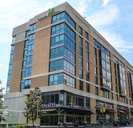 exterior of Midtown Crossing Apartments building with shops on first floor and 5 floors of apartments
