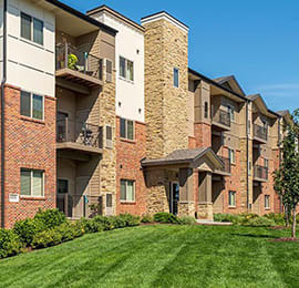 an apartment building with a green lawn in front