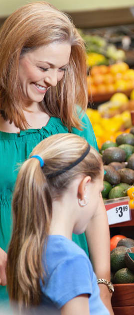 a woman and a girl looking at fruit in a market