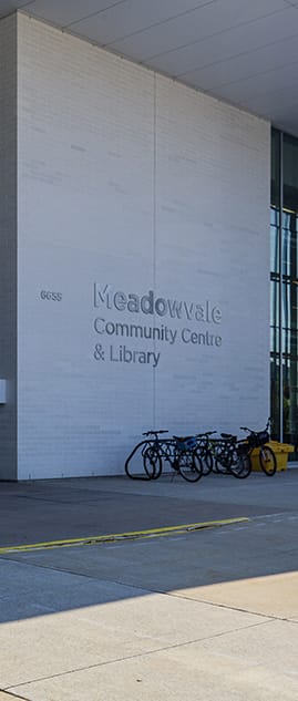 a group of bikes parked outside the meadowvale community centre and library building