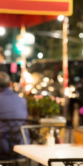 A man is sitting at a table under a red and yellow awning.