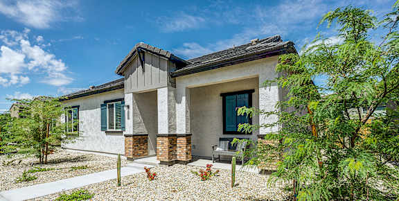 A modern house with a grey roof and a gravel driveway.