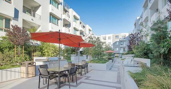 A patio with a table and chairs under a red umbrella at Woodley Sara Apartment, Van Nuys, 91406