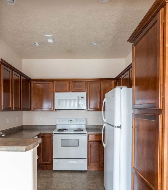 an empty kitchen with wooden cabinets and white appliances